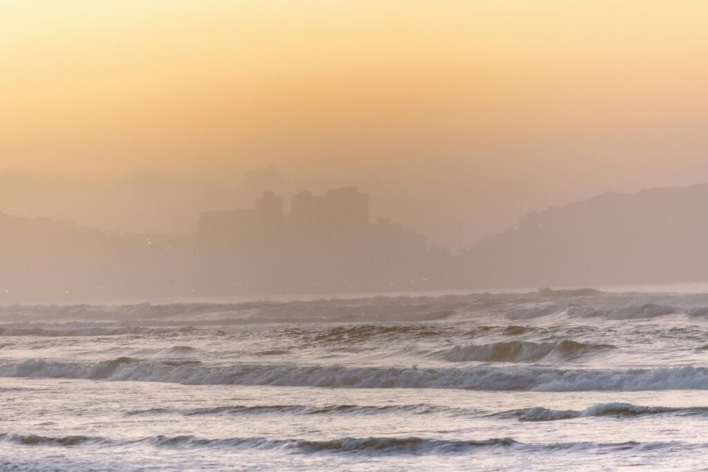 Calm waves and a warm sunset set a peaceful scene at Guarujá Beach, Brazil.
